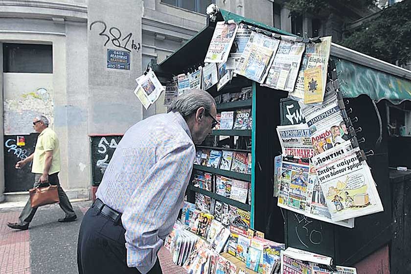 CRISIS. Una persona lee titulares de la prensa en Atenas, en medio de una tensa situación financiera