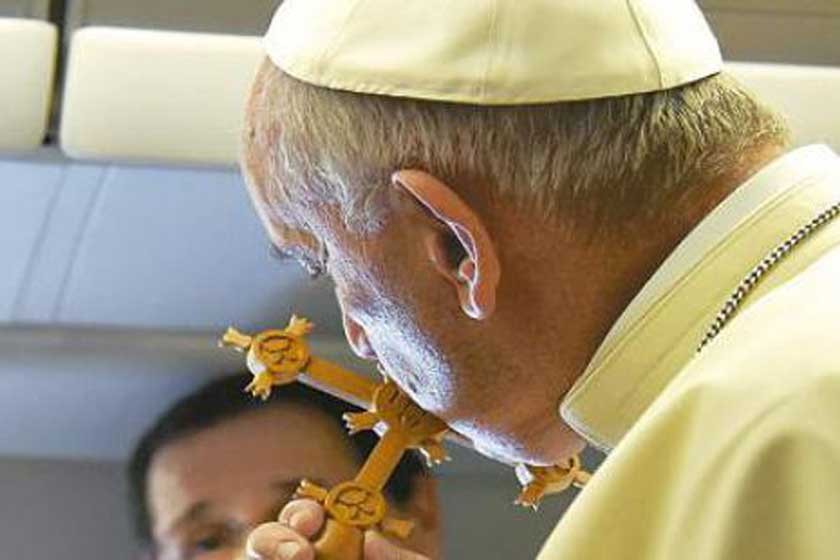 visita. El Papa besa la cruz misional cruceña que le obsequió una periodista boliviana durante el vuelo del Vaticano