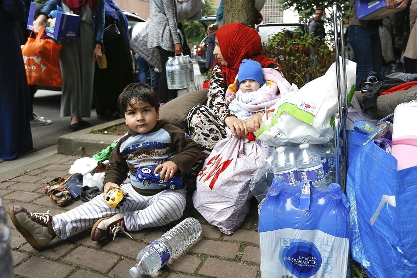Una mujer refugiada y sus hijos permanecen en la calle ante una oficina para extranjeros en Bruselas, Bélgica. Foto: EFE
