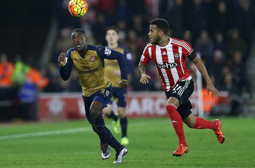 Joel Campbell (i) del Arsenal intenta controlar el balón ante la marca de un defensor de Southampton.