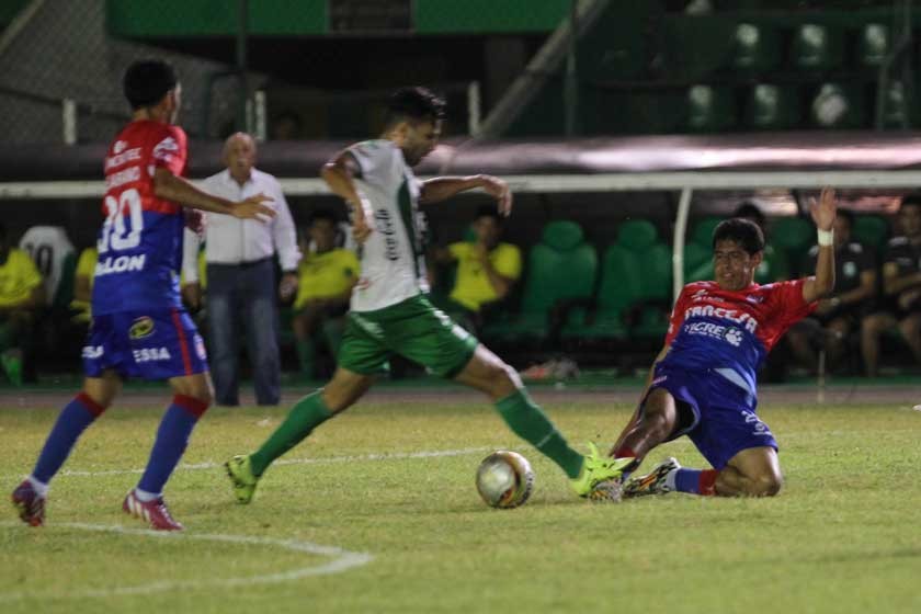 El volante estudiantil Edson Zenteno se barre al piso en su intento de robarle el balón a un jugador refinero