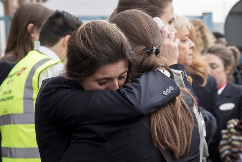 Dos trabajadoras del aeropuerto se abrazan mientras son evacuadas junto a los pasajeros de la zona aeroportuaria. EFE