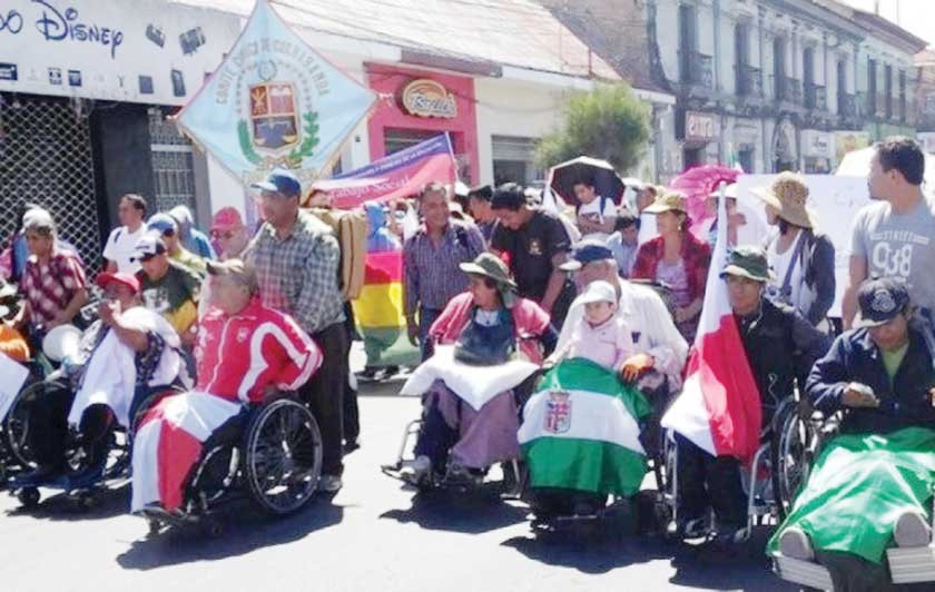 MOVILIZADOS. Los discapacitados que se dirigen a La Paz, ayer, durante una pausa en una población cercana a Cochabamba.