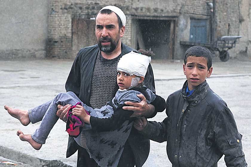 VIOLENCIA. Un hombre lleva a una niña en brazos herida en un atentado cerca del Ministerio de Defensa en Kabul.