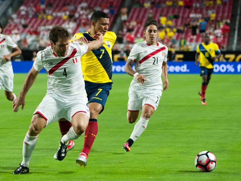 El centrocampista ecuatoriano Jefferson Montero pelea por el balón en medio de dos jugadores peruanos