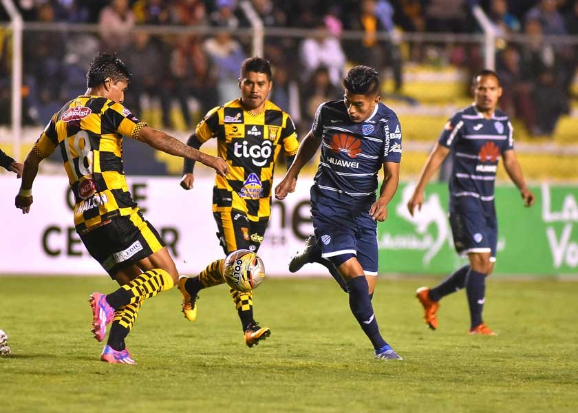 El atigrado Jair Torrico (i) y el bolivarista Erwin Saavedra (d) intentan controlar el balón en el partido jugado anoche