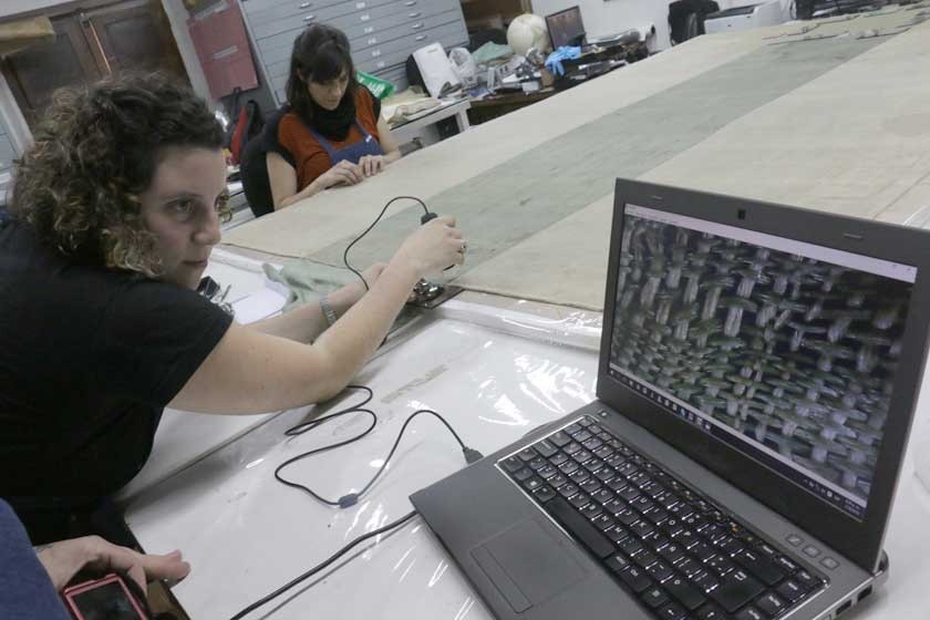 RESTAURADORAS. Las especialistas argentinas analizando las fibras de la bandera de Macha con un microscopio