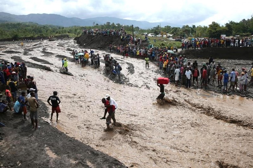 Personas intentan cruzar el río La Digue, debido al derrumbe del único puente de la zona en Haiti. Foto: EFE