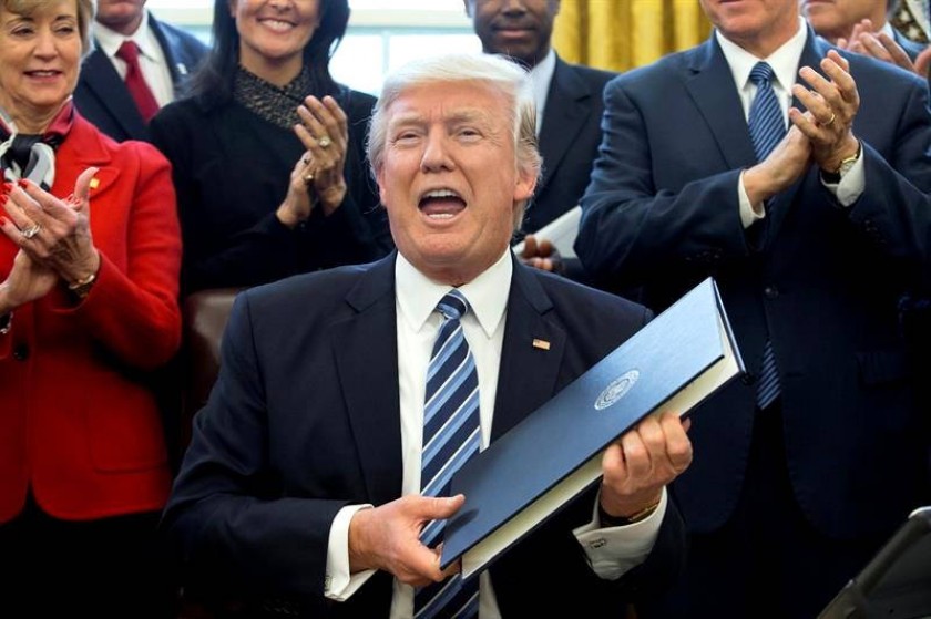 Donald Trump (c) firma la orden ejecutiva titulada "Plan Integral para la Reorganización del Poder Ejecutivo". EFE