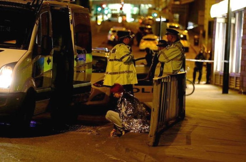 Una mujer es vista sentada en una calle cerca al Manchester Arena, junto a un grupo de policías, tras explosiones. EFE