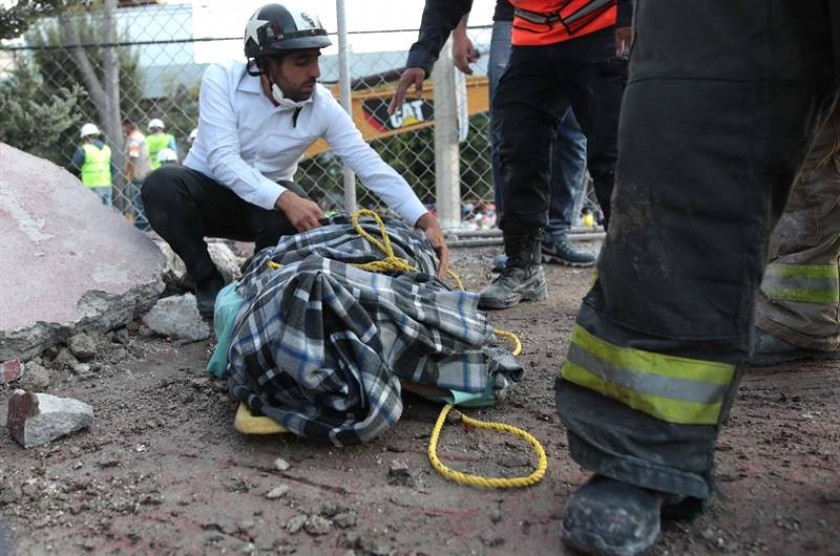 Rescatistas envuelven el cuerpo de una víctima encontrada en el área de unos edificios colapsados hoy, martes. EFE