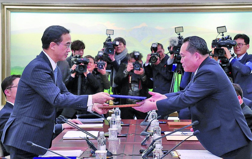 ENCUENTRO. El delegado de Corea del Sur, Cho Myoung-gyon (i), intercambia un documento con el delegado de Corea del Nort