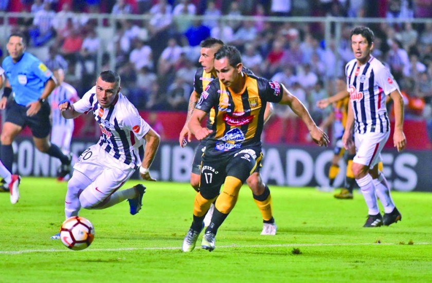 El atigrado Marvin Bejarano (c) presiona en la marca al paraguayo Antonio Bareiro (i) en el partido jugado ayer, en...