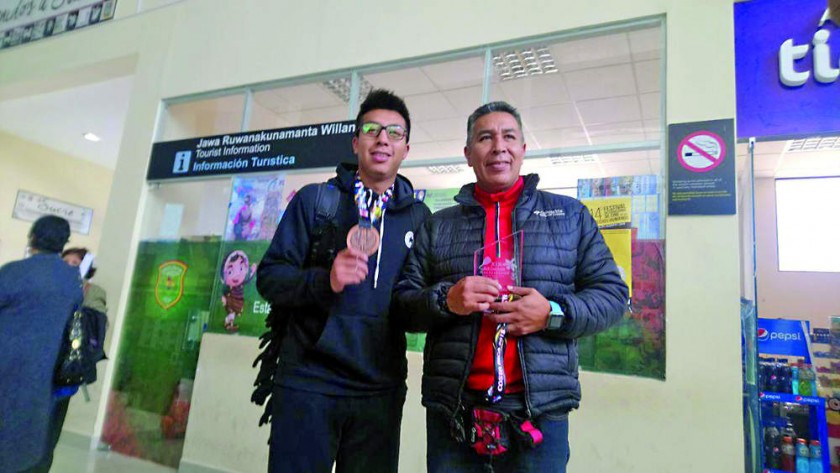 Conrrado Moscoso (i) junto con su padre y entrenador llegaron ayer a Sucre tras lograr el tercer lugar y la medalla...