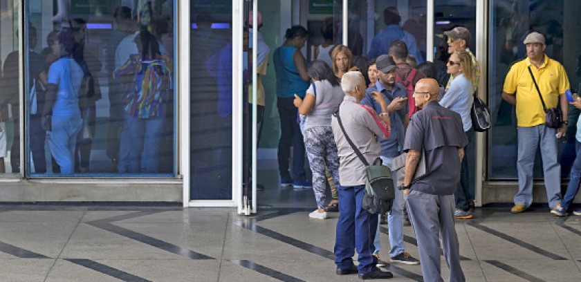 ENERGÍA. Ciudadanos aguardan la atención en un banco en Caracas después de un prolongado corte de energía eléctrica...