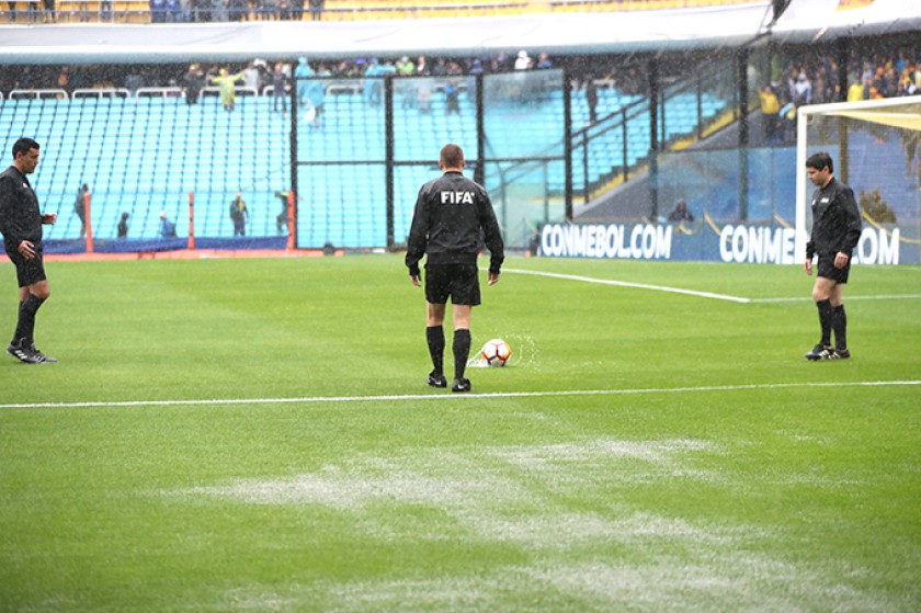 El equipo arbitral inspecciona el campo de juego de la Bombonera