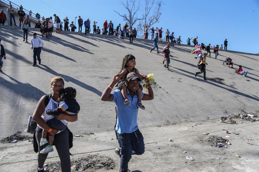 Grupos de personas tratan de cruzar hoy, la garita El Chaparral, de la ciudad de Tijuana, en el estado de Baja Californi