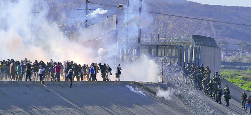 REPRESIÓN. Migrantes buscaron trepar el muro fronterizo con Estados Unidos y fueron recibidos con gases lacrimógenos.