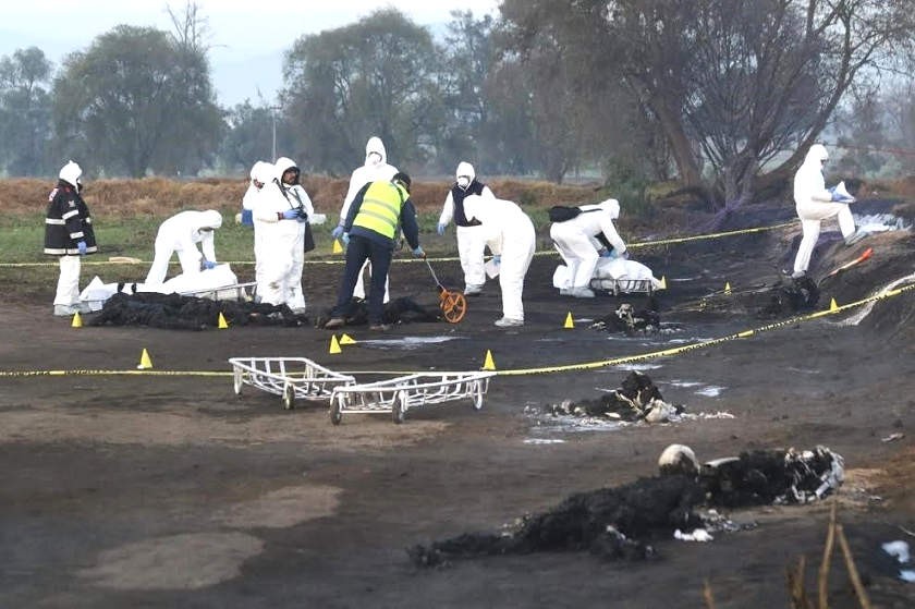 Expertos forenses trabajan en el sitio donde 66 personas murieron al estallar una toma clandestina de gasolina. EFE
