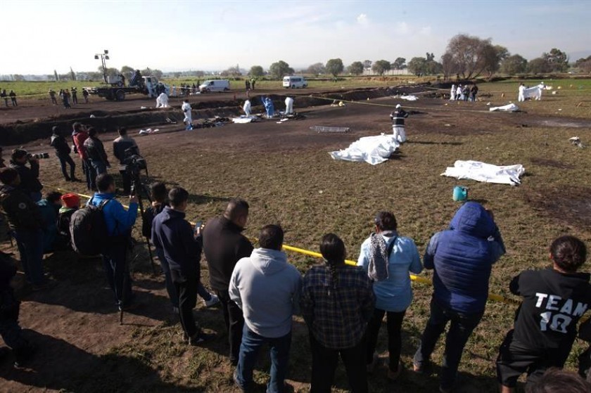 Expertos forenses registran la zona cerca de una toma clandestina de gasolina de Pemex que explotó el viernes. EFE