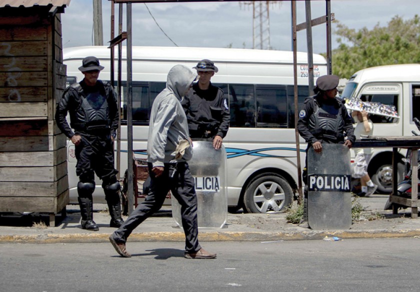 TENSIÓN. Agentes antidisturbios de la Policía resguardan una parada de autobús frente a la Universidad Centroamericana (