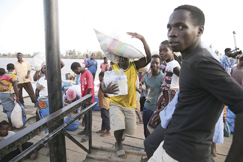MOZAMBIQUE. Personas cargadas con alimentos a su llegada al puerto de Buzi, tras el paso del ciclón Idai.