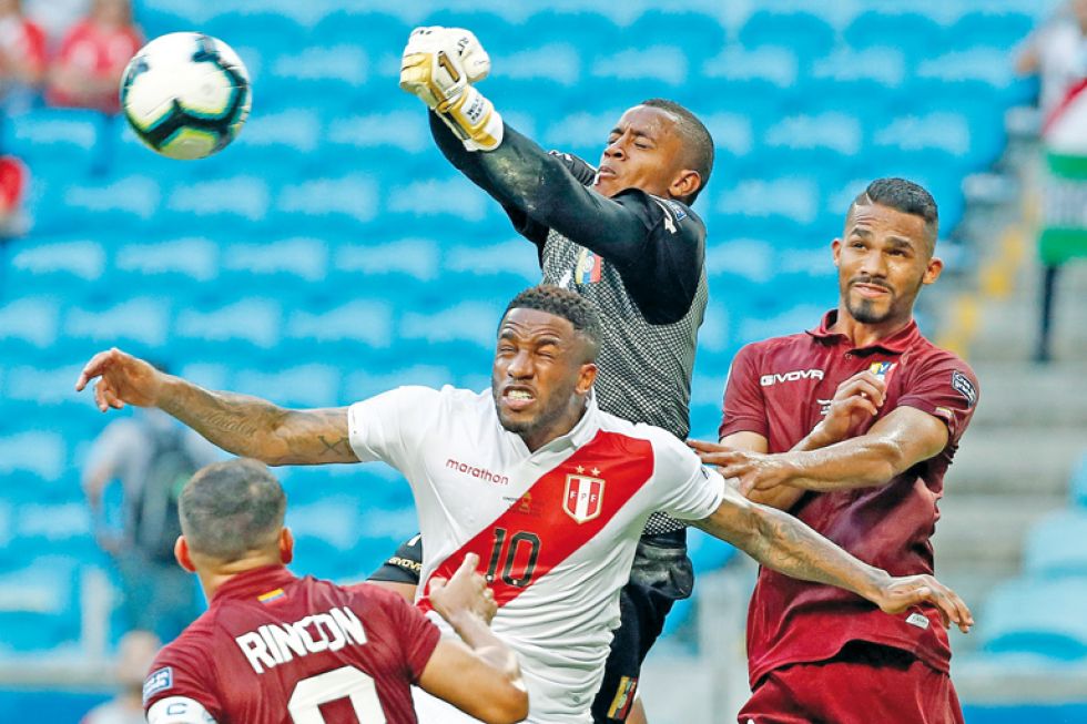 El arquero Wuilker Fariñez (arriba) de Venezuela rechaza un balón ante Jefferson Farfán (c) de Perú en el Estadio Arena do Grêmio de Porto Alegre.