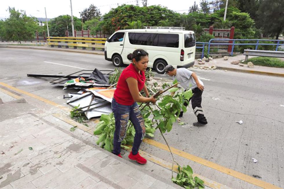 TENSIÓN. Empleados municipales retiran escombros de una avenida de Tegucigalpa luego de las violentas protestas del miércoles.