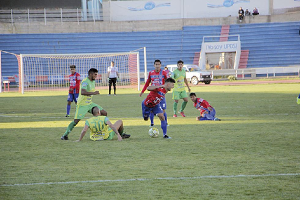 El tarijeño Pablo Gómez (30) se barre contra el argentino Víctor Cabral (c), ayer, en el partido entre Universitario y Nacional Senac, jugado en Sucre.