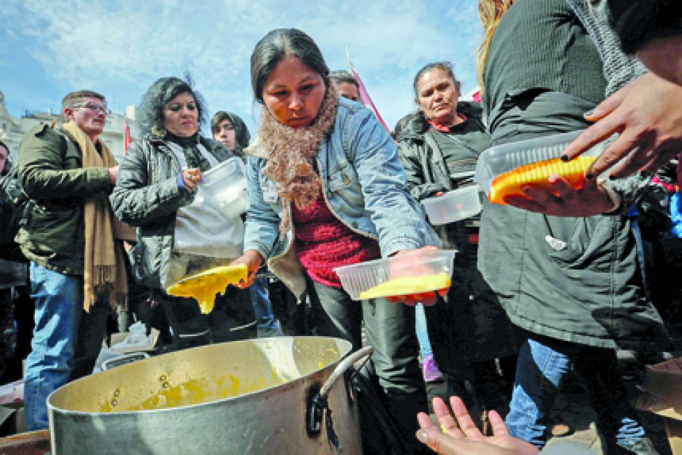 PROTESTAS. Mujeres reparten comida durante una movilización contra el gobierno de Mauricio Macri por la crisis económica.