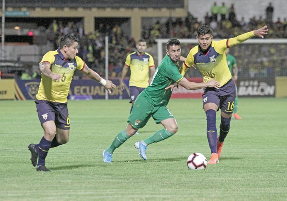 El delantero boliviano Rodrigo Ramallo (c) intenta quitarle la pelota al defensor ecuatoriano Xavier Arreaga.