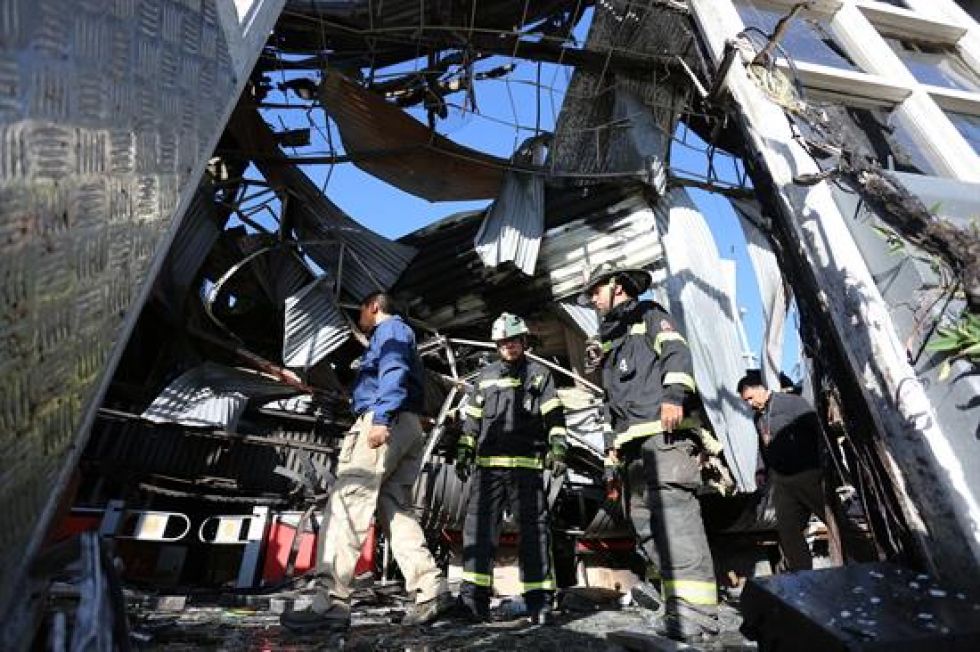 Personal policial y de bomberos inspecciona un supermercado en el que ocurrió una explosión después de ser saqueado.