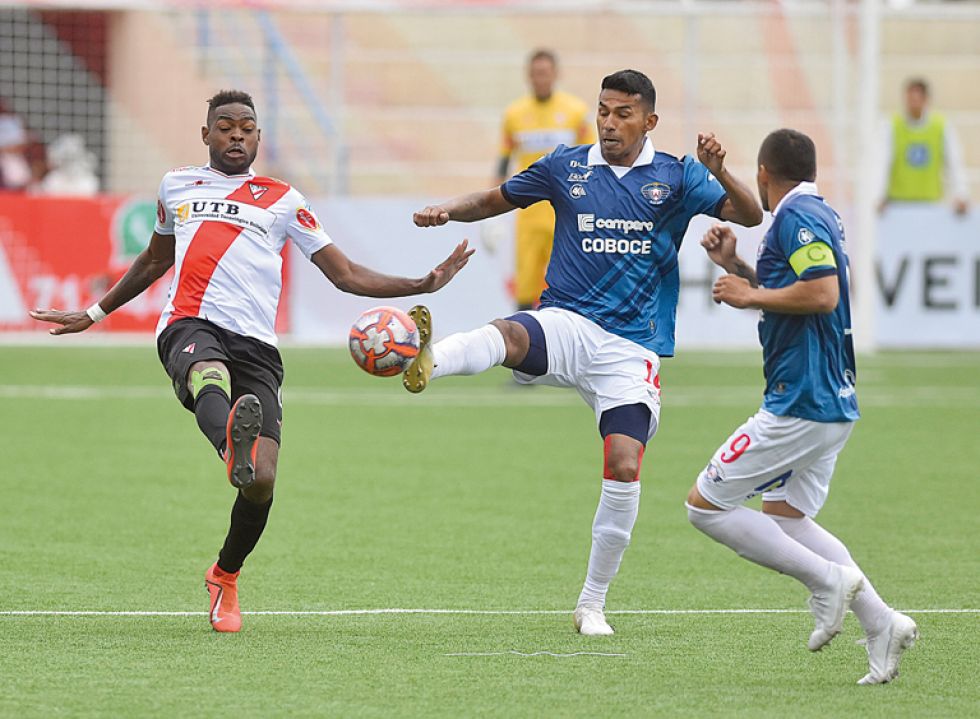El delantero aviador Gilbert Álvarez (c) pelea por el balón con el defensor millonario Marc Enounba (i) en el partido jugado ayer, en Villa Ingenio.
