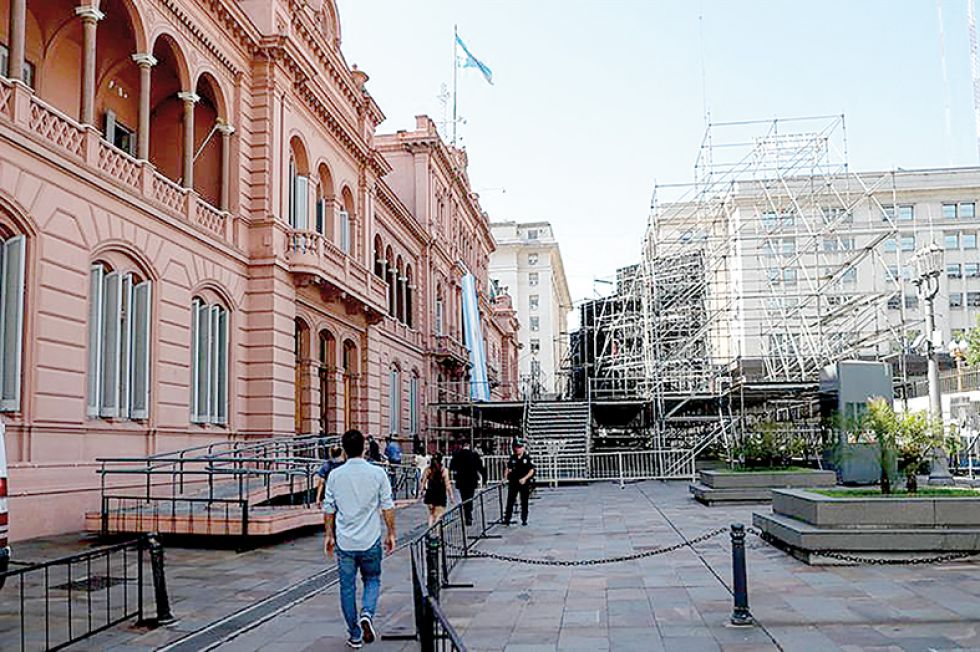CEREMONIA. Un grupo de personas camina junto a los trabajos de preparación para la investidura de Alberto Fernández.