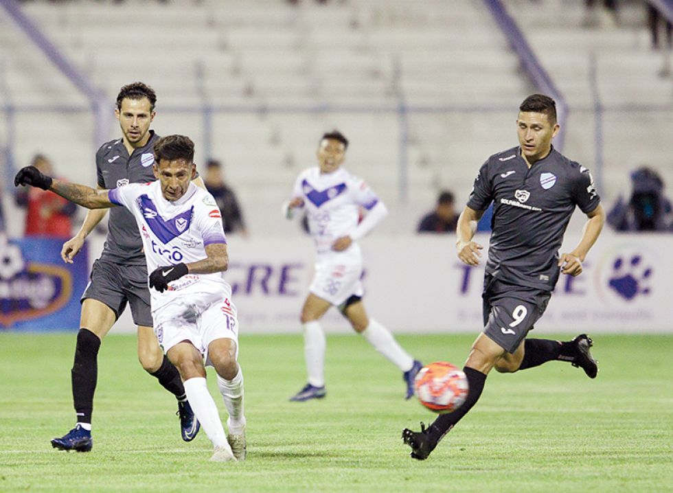 El delantero académico Vladimir Castellón intenta dominar el balón ante la presión del defensor santo Jair Torrico (i).