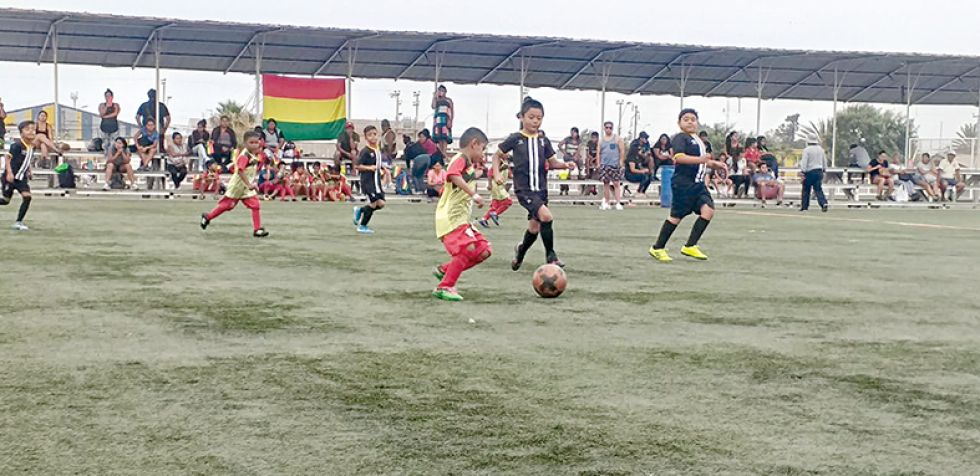 Los niños campeones de la Escuela de Fútbol “Semillero Diablos de Oro” en Chile; abajo, el pasaje de un partido.