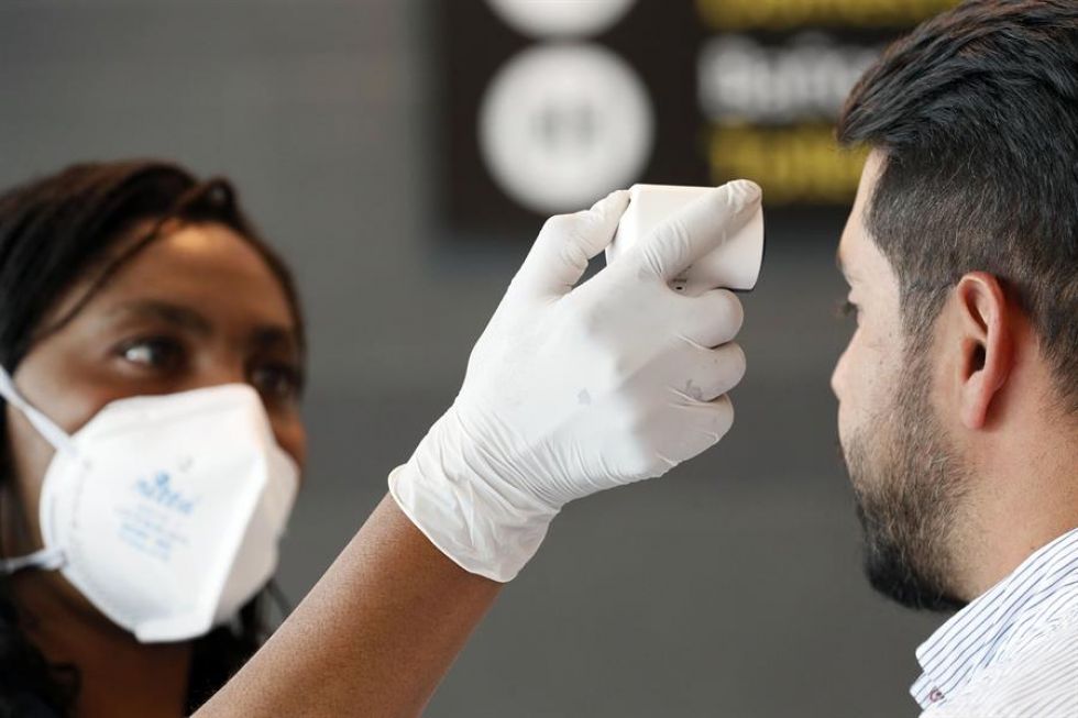 Funcionarios toman la temperatura de los ciudadanos que llegan al aeropuerto internacional El Dorado, como parte de las medidas de prevención en Colombia.
