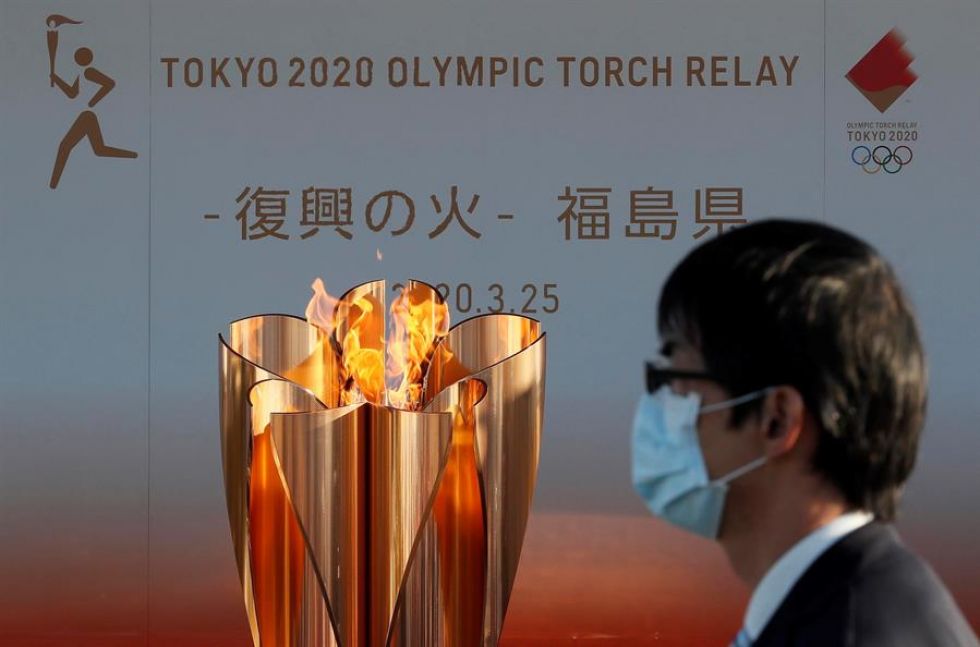 Un hombre con mascarilla pasa junto a la antorcha olímpica en la localidad de Iwaki, Japón.