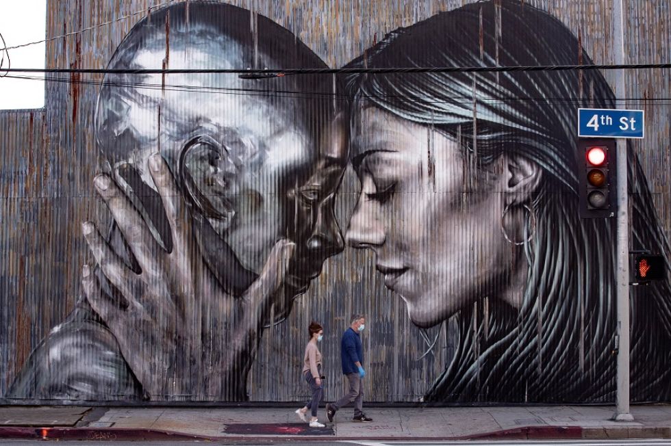 Una pareja pasea junto a un mural en el Distrito de las Artes en Los Ángeles, durante la crisis sanitaria causada por el coronavirus.