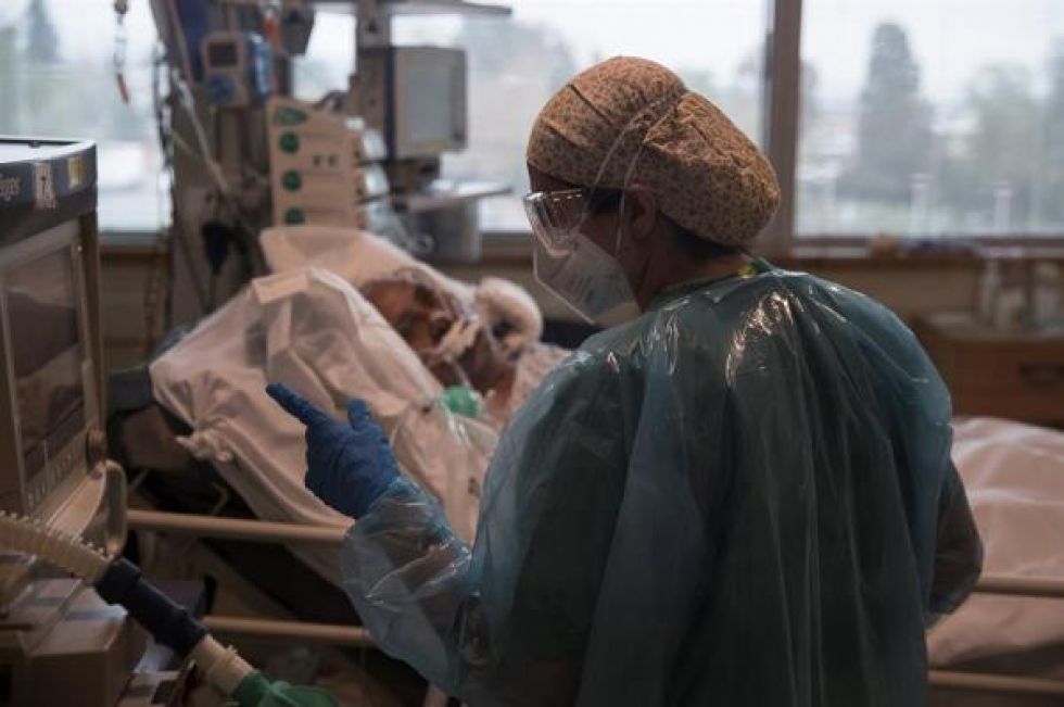 Una doctora del Hospital Militar de Santiago, revisa los signos vitales de un paciente con covid-19 que permanece entubado.
