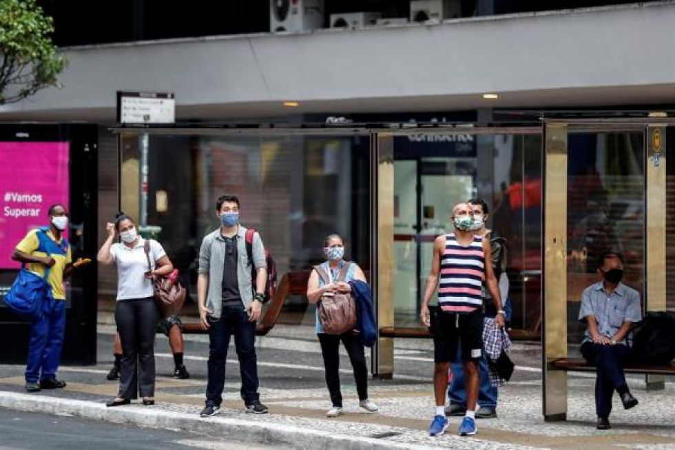 Personas con tapabocas esperan en la parada de autobús este martes en la ciudad de Sao Paulo (Brasil).
