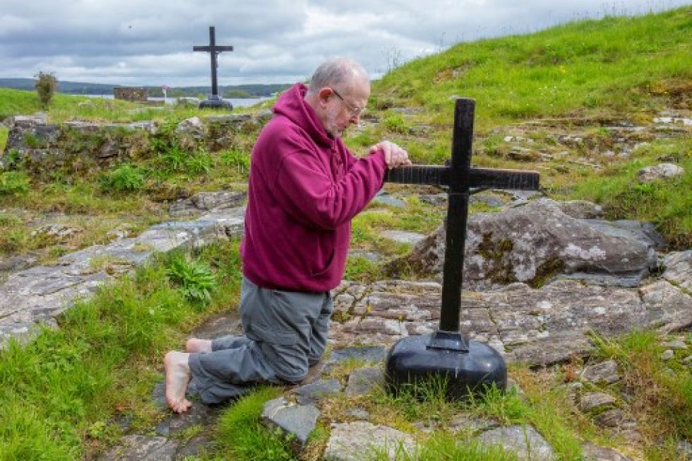 El padre Flynn reza en las camas penitenciales donde los peregrinos van a rezar al Purgatorio de San Patricio en Lough Derg.