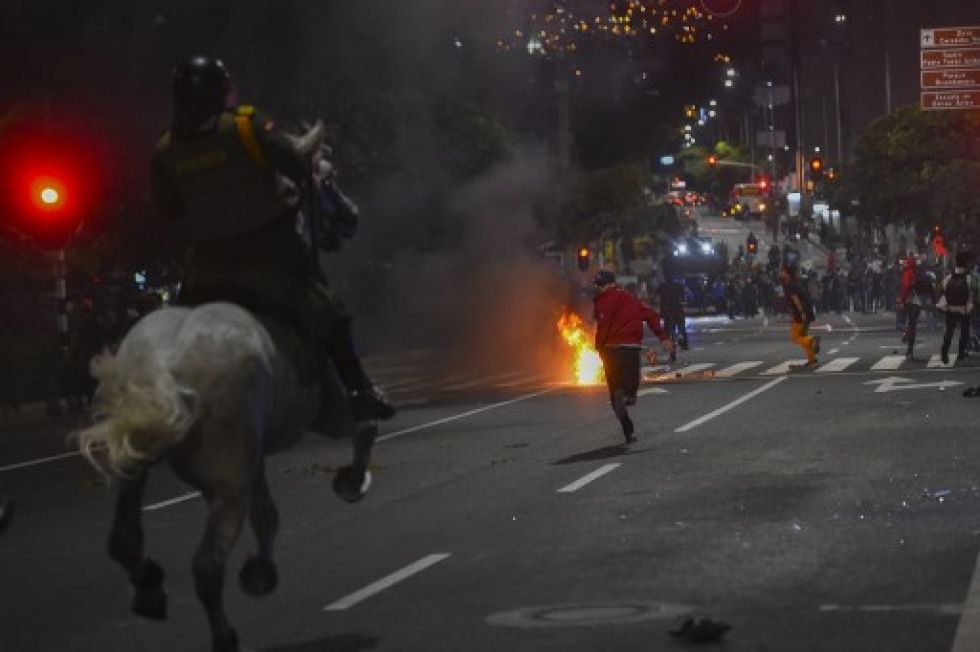 Los manifestantes corren mientras la Policía montada a caballo los persigue durante una protesta en Medellín.