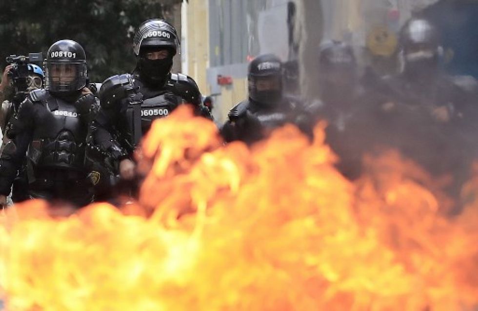 La policía antidisturbios camina detrás de una barricada contra incendios colocada por manifestantes.