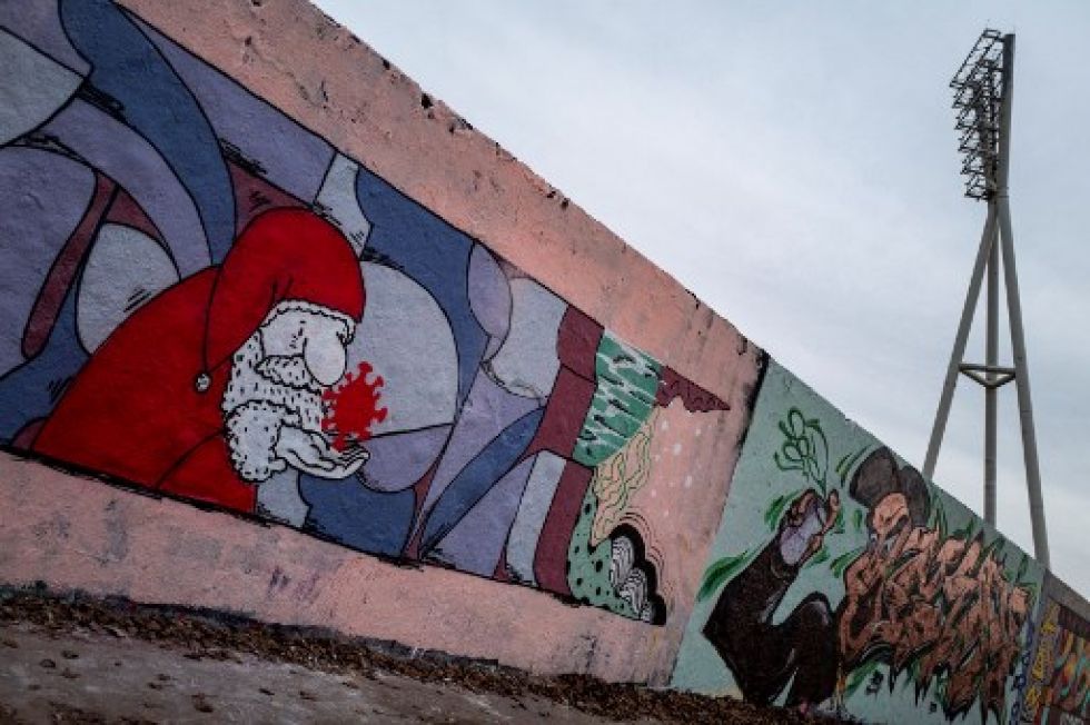 Una pintura mural presenta una imagen de Santa Claus sosteniendo una molécula de SARS-CoV-2, en Berlín.