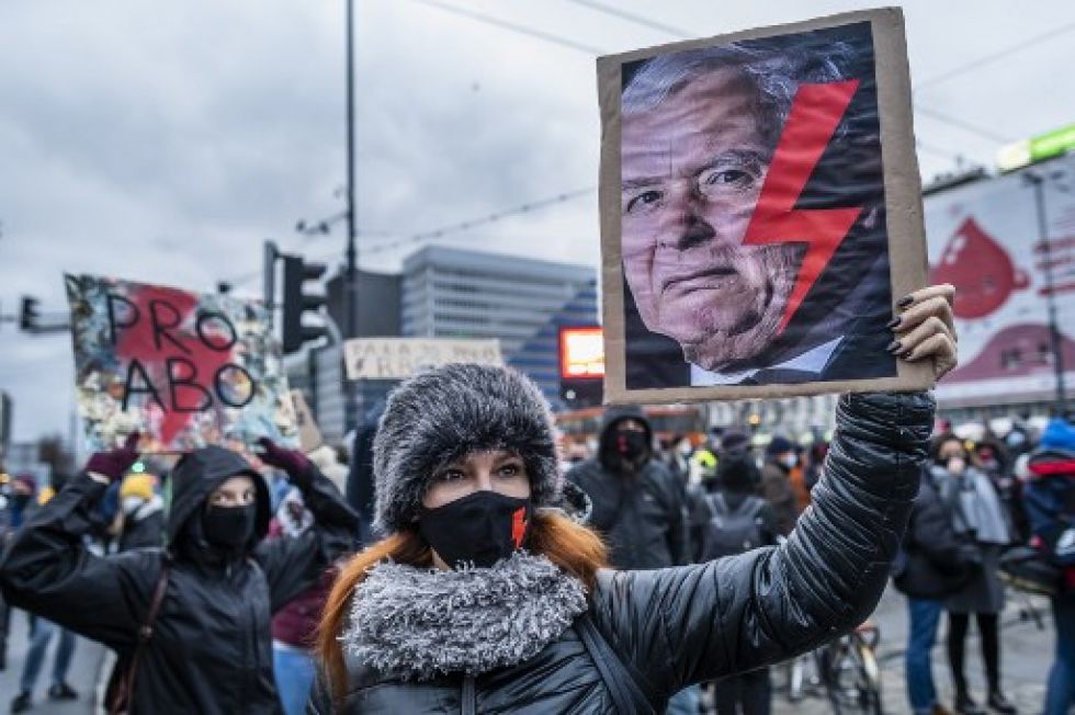Una mujer sostiene un cartel con el rostro de Kaczynski con un rayo rojo, símbolo del movimiento de huelga de mujeres, en una protesta en 2020.