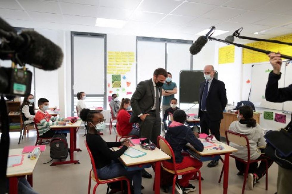 El presidente Emmanuel Macron (C) se dirige a los alumnos durante una visita a una escuela primaria en Melun, donde reinician las clases.