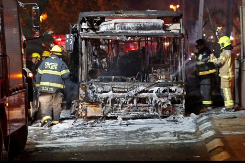 Bomberos trabajan en un bus incendiado a causa de un cohete palestino que impactó cerca de un poblado de Tel Aviv.