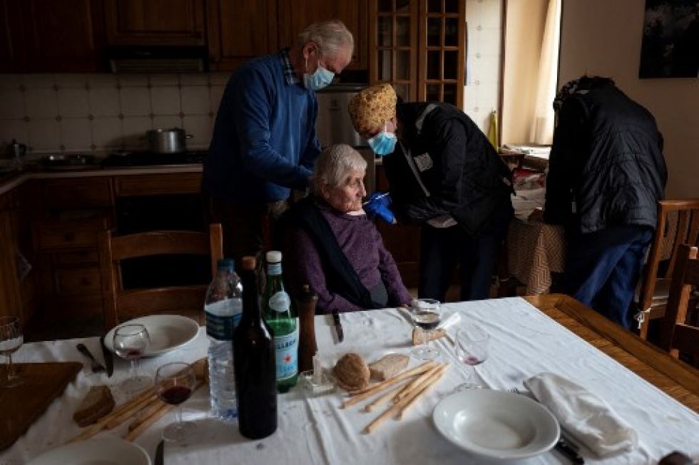 Una anciana recibe su vacuna en una pequeña localidad del norte de Italia. La vacunación masiva avanza lentamenta, mientras surgen grupos extremistas que cuestionan su eficacia.