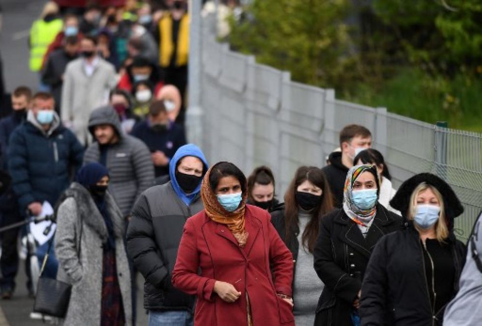Personas hacer fila para recibir una vacuna covid-19 en un centro de vacunación temporal en Bolton, noroeste de Inglaterra, este lunes.